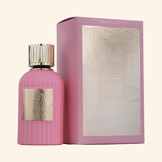 Pink perfume bottle and packaging with silver accents on a white background. Discover Paris Corner Qissa Pink UK. A chic women's EDP with apple, coconut, rose, violet & a woody vanilla base. Avent-us for Her alternative. Shop now!